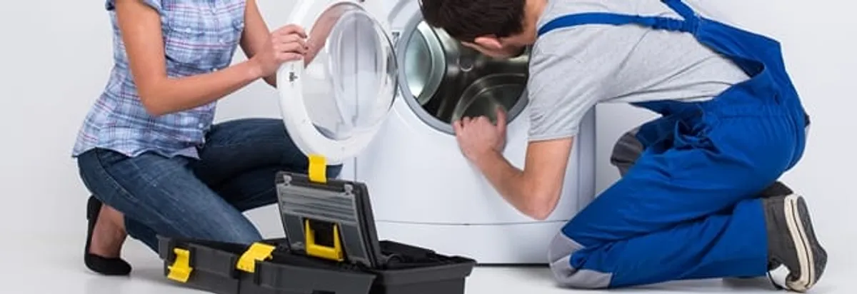 Washer repair technician inspecting a front-load washing machine with tools in Tallahassee, FL