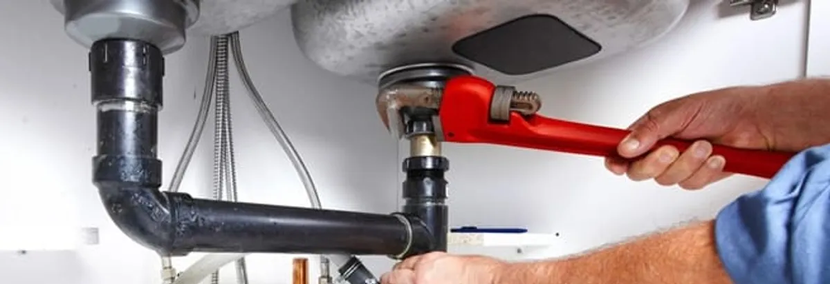 Garbage disposal repair technician tightening the sink drain and disposal connection in Tallahassee, FL
