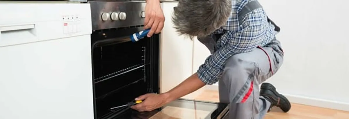 Oven repair technician inspecting and servicing an electric oven in Tallahassee, FL