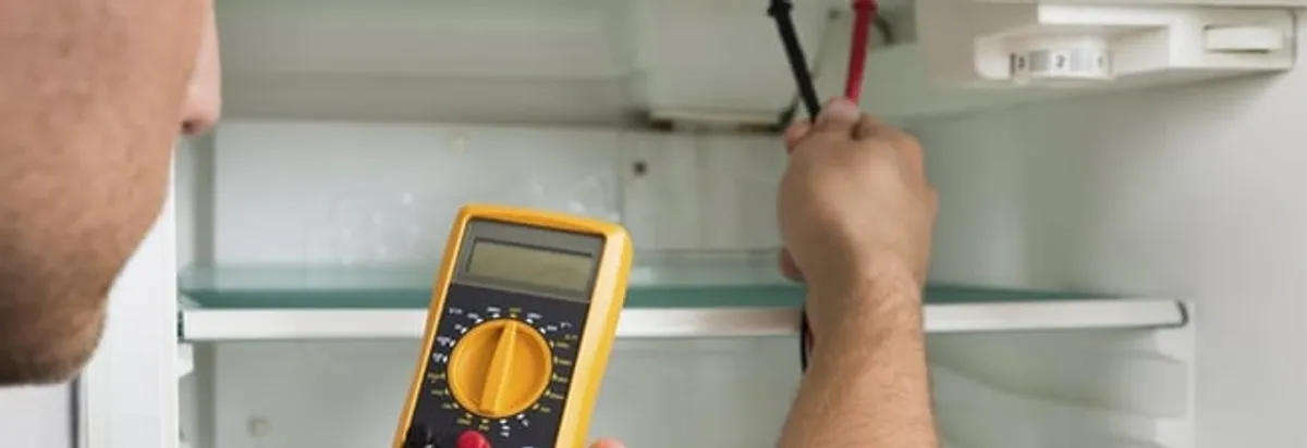 Refrigerator repair technician testing electrical components with a multimeter in Tallahassee, FL