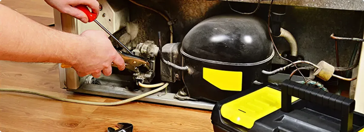 Refrigerator repair technician fixing the compressor and wiring in Tallahassee, FL